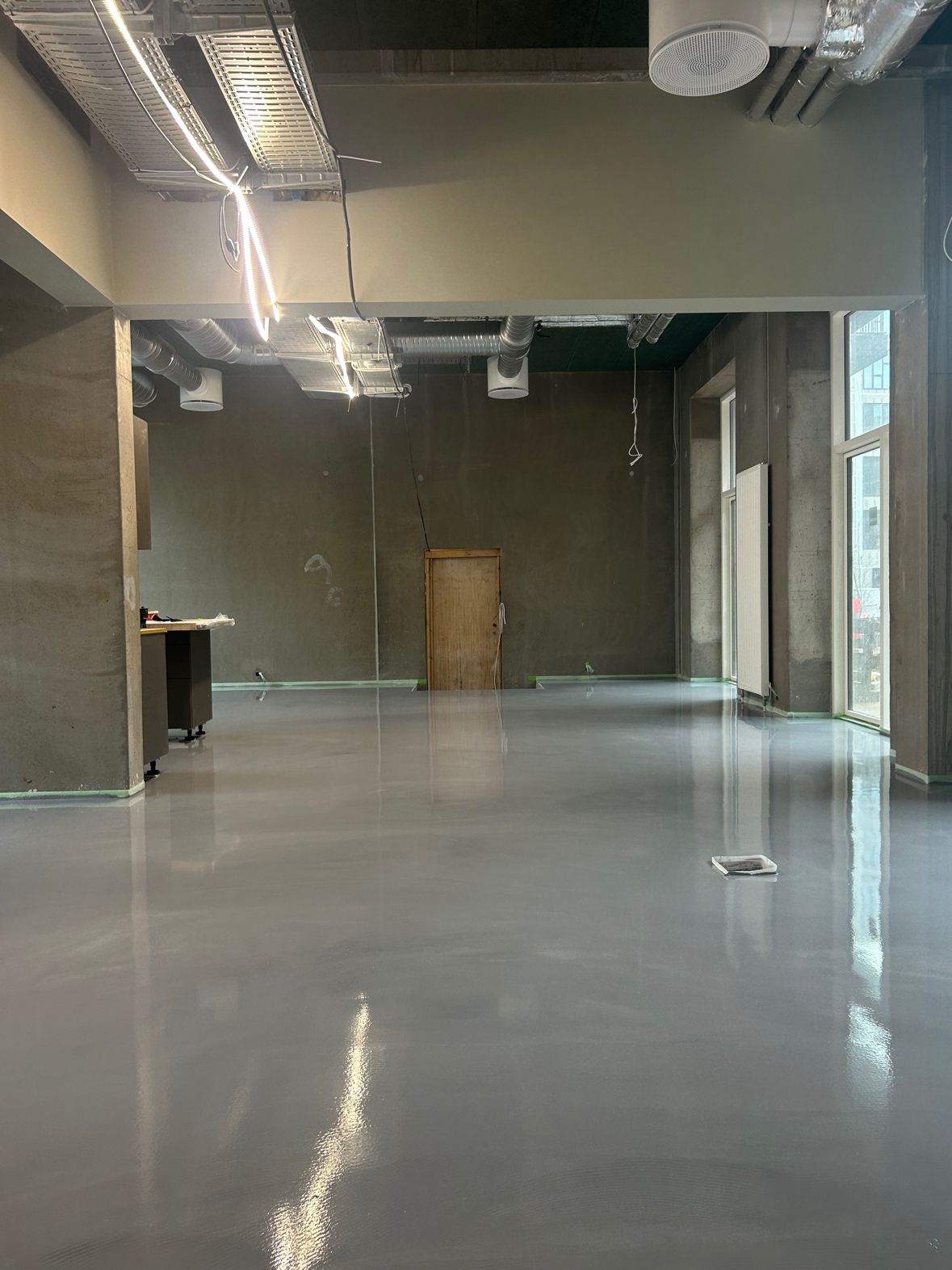 Seamless grey mineral floor running through a communal ground-floor space at UN17 Village