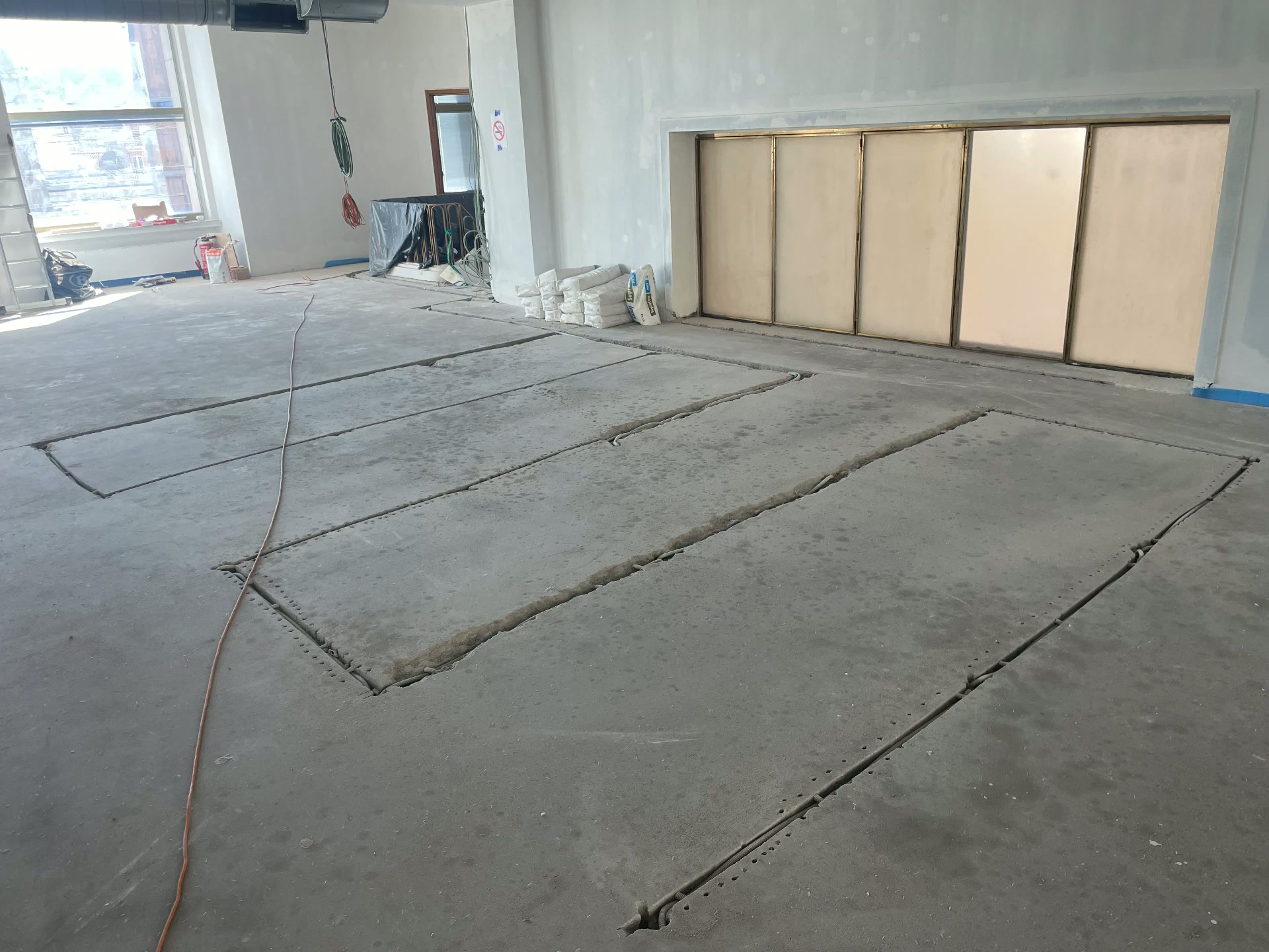 Substrate preparation inside the old Brussels-North station: utility channels cut into the concrete slab before the mineral floor is laid