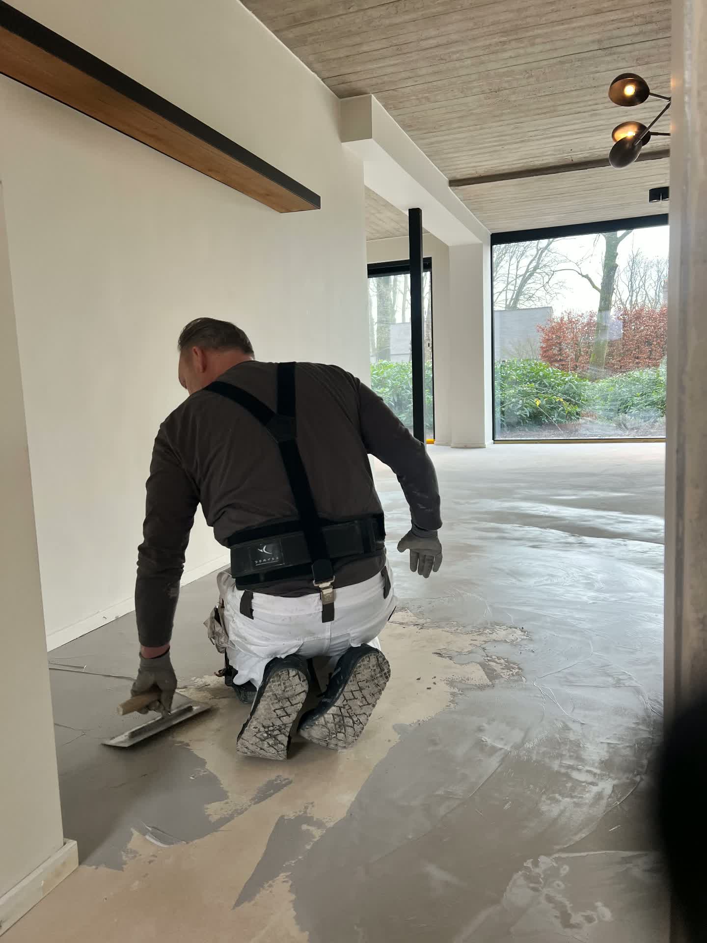Applicator trowelling the mineral floor finish in a private residence near Antwerp