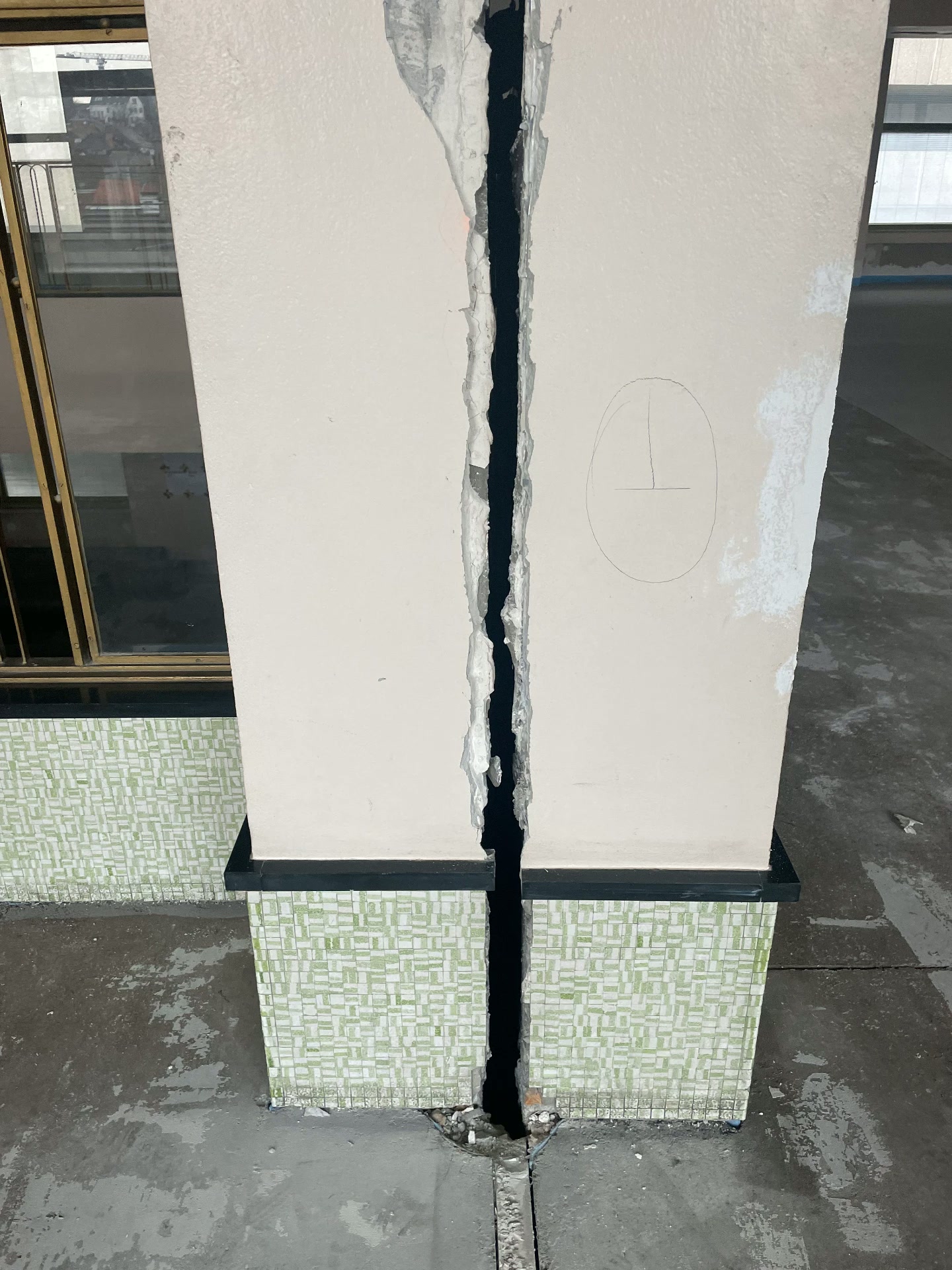 Cracked pillar base with tiled surround inside the old Brussels-North station, marked out for repair before the system is applied